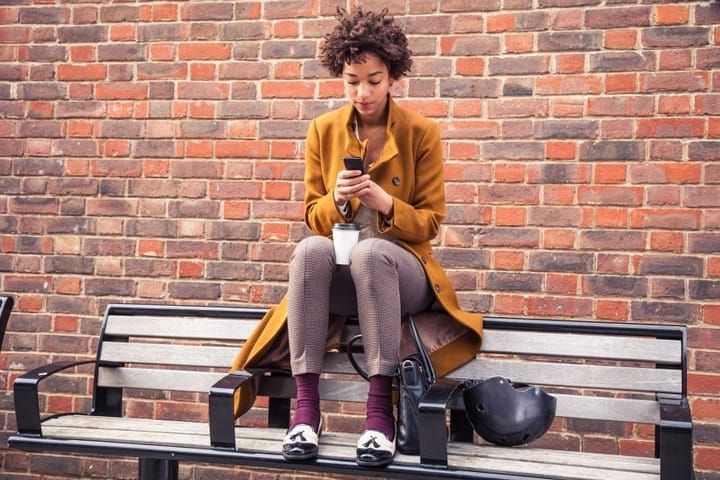 black woman afro bench texting