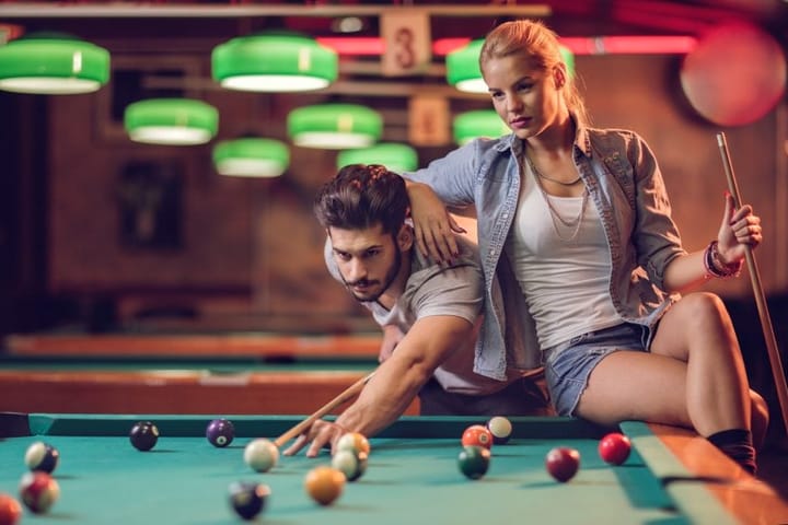 Young couple playing snooker in a pool hall.