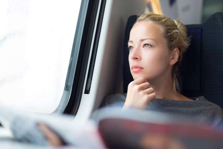 Thoughtful young lady reading while traveling by train.