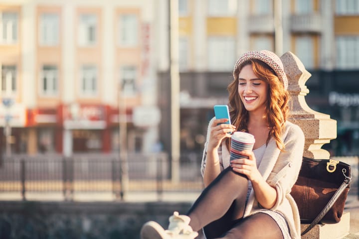 Smiling woman with phone text messaging outdoors