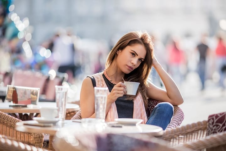 Young woman sitting in a city cafe and thinking about something.