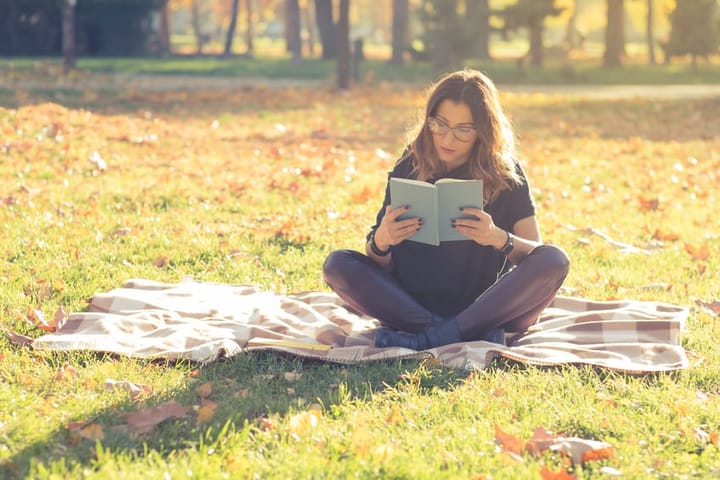 Carefree young woman reading a book and relaxing in the park.