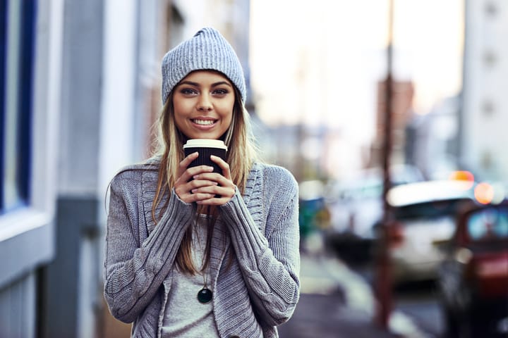 Portrait of a beautful young woman standing with a takeaway coffee in the city