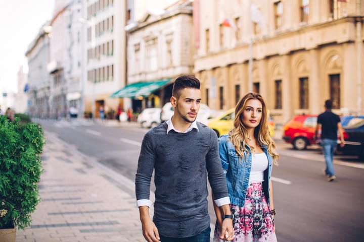 Young couple holding hands and walking city streets.