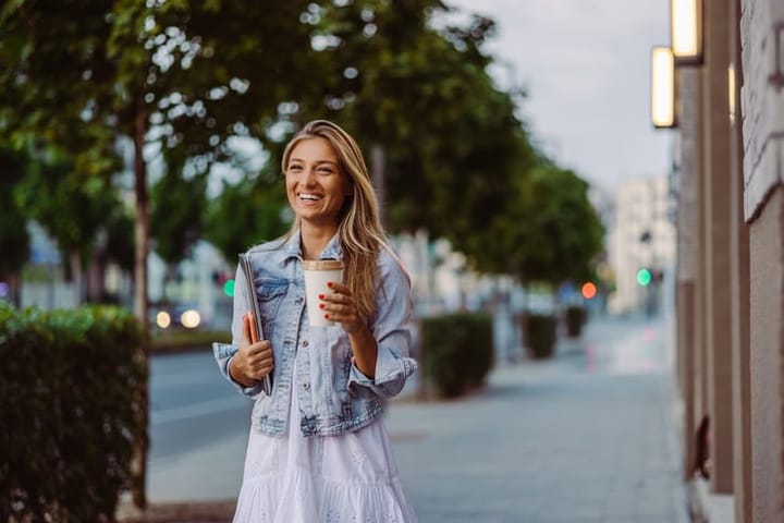 smiling woman outdoors with coffee