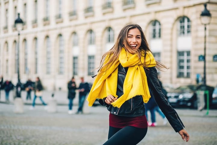 Young woman smiling walking outdoors Paris city, with copy space.