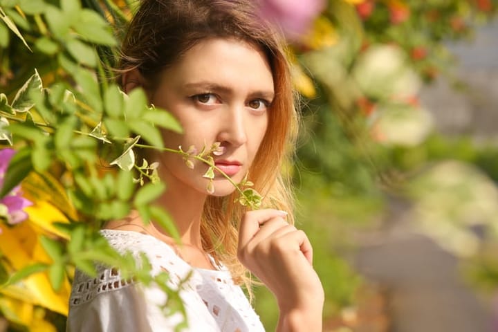 Head shoot of young woman surrounded by flowers.