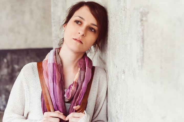 Thoughtful woman leaning against wall