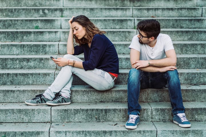 Couple looking bored and gloomy sitting on the stairs outside