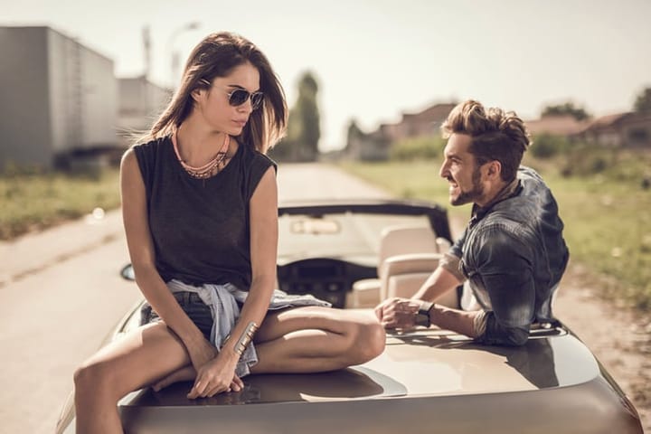 Young couple enjoying in a day while relaxing on cabriolet. Focus is on woman.