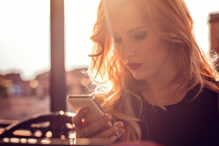 young woman texting sunset outdoors summer