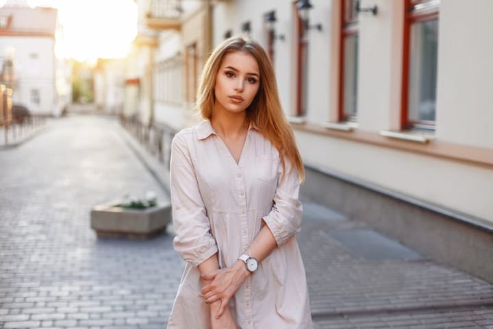 Young beautiful girl in pink dress walking in the city at sunset