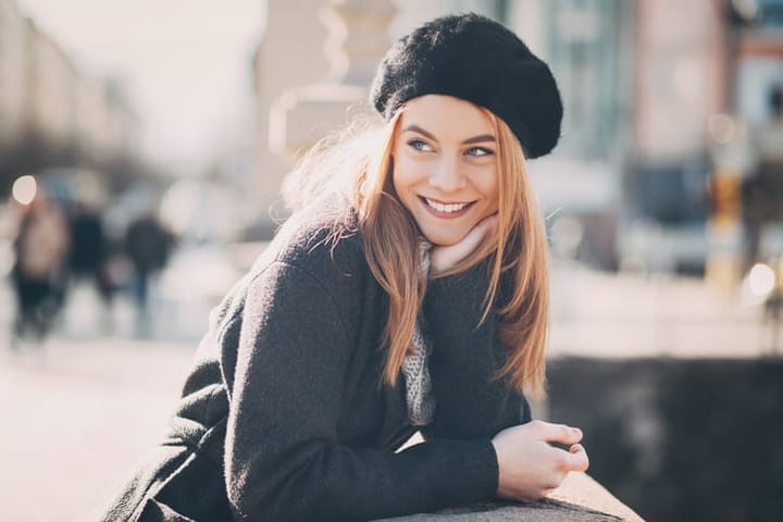 Portrait of a smiling young woman under the sunlight at city scene, with copy space