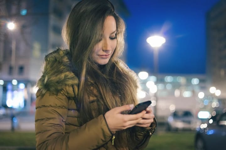 woman texting outdoors at night