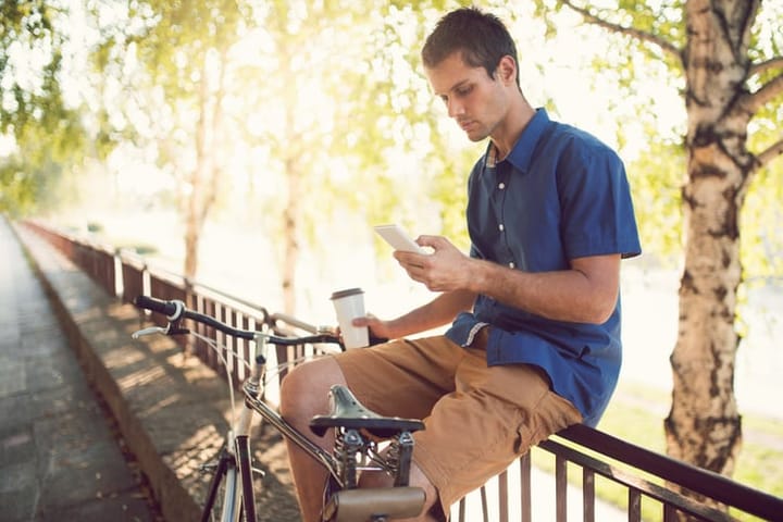 Young caucasian man texting a message on his smart phone.