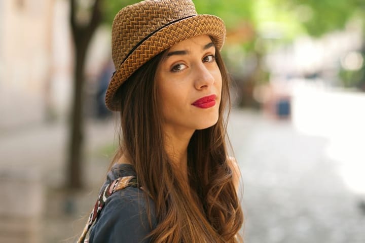 Portrait of beautiful woman looking at camera.She is wearing a hat and have a red lipstick