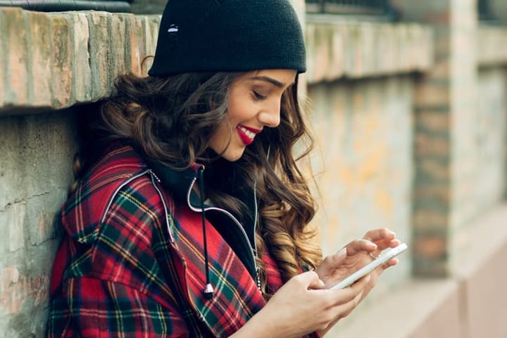 smiling woman beanie hat using mobile