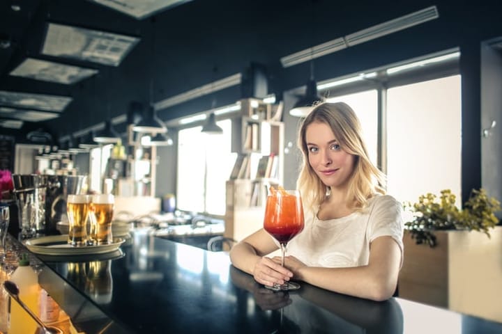 Young woman is drinking a cocktail in a bar