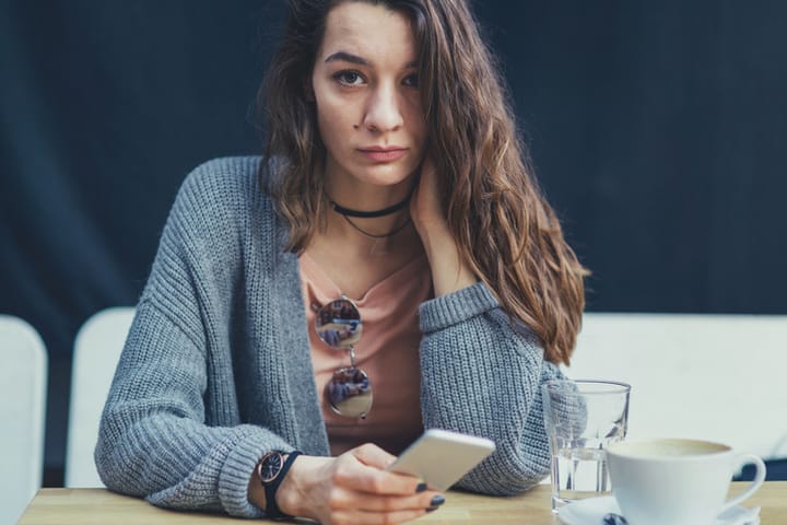 Girl holding her phone received bad news and is sad in the café