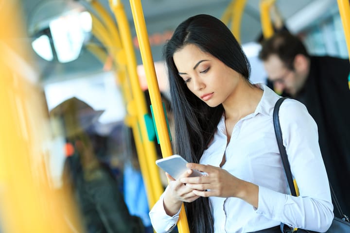 Pensive young woman using smart phone in a bus