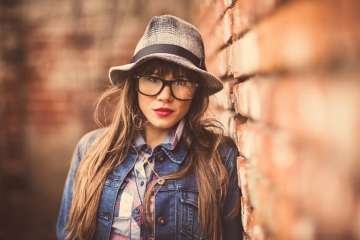 Cool hipster girl posing next to a red brick wall