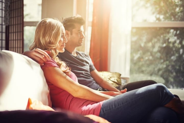 couple at home on couch watching tv while sitting on couch