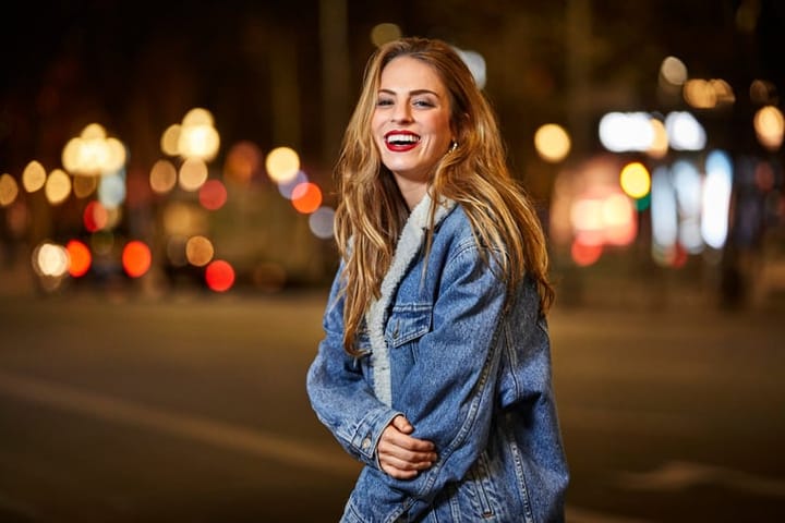Portrait of happy woman standing on road at night