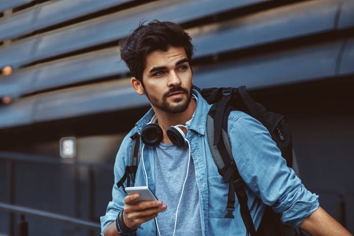 bearded man in denim clothes holding mobile