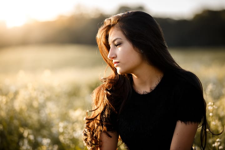 Serious brunette girl posing sideways in a plantation field.