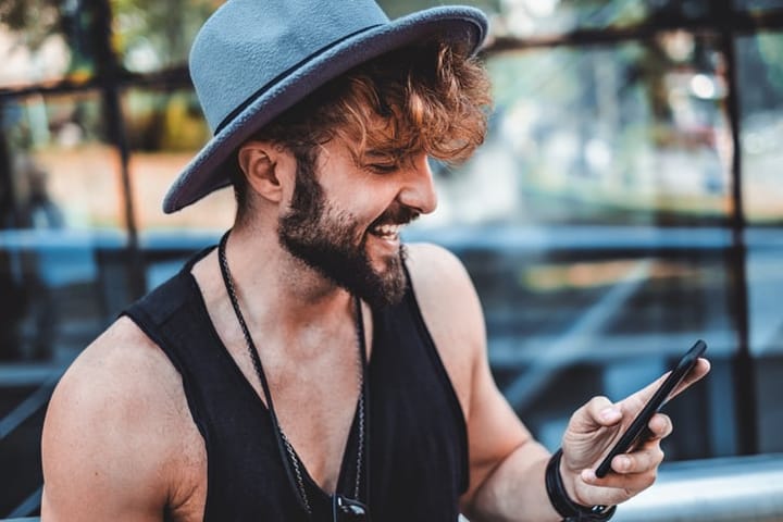 Hipster with hat smiling and reading message