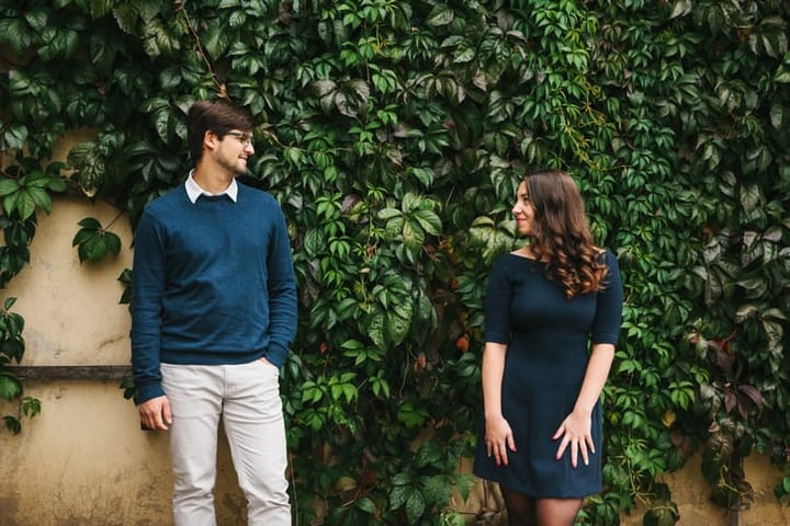 A loving young beautiful couple of students from Europe communicate in a park near a wall with ivy. Close feelings and emotions between people.