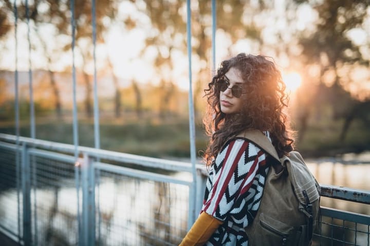 curly haired woman with sunglasses in sunset
