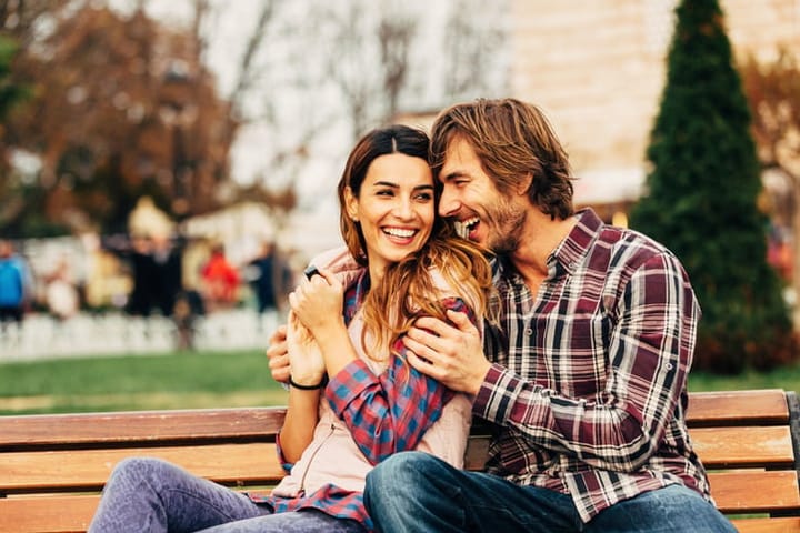 Happy young couple sitting on a bench.