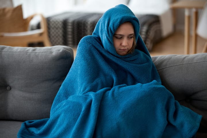 Woman wrapped in a blanket at home.