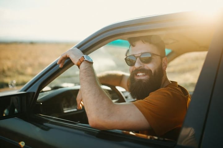 man in a car with a beard smiling