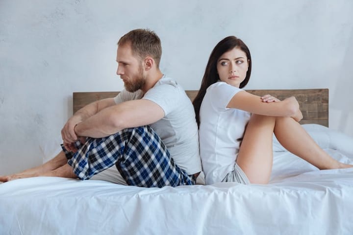 Millennial couple sitting on bed after argument