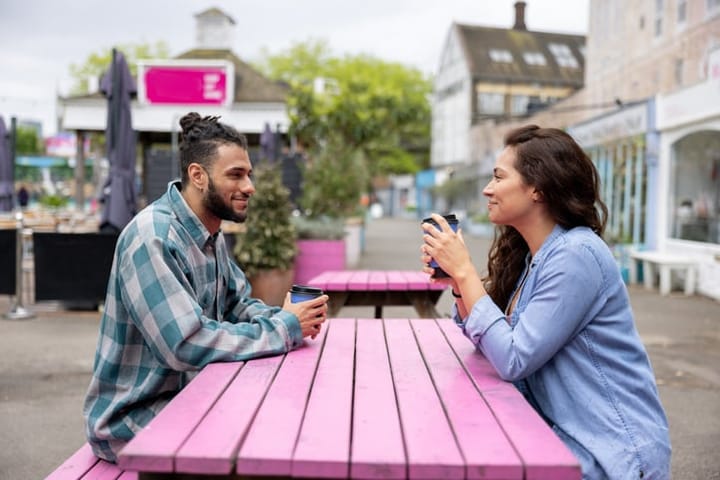 young dating couple sitting at pink table