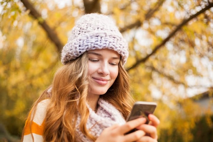 girl with wool hat looking at smartphone