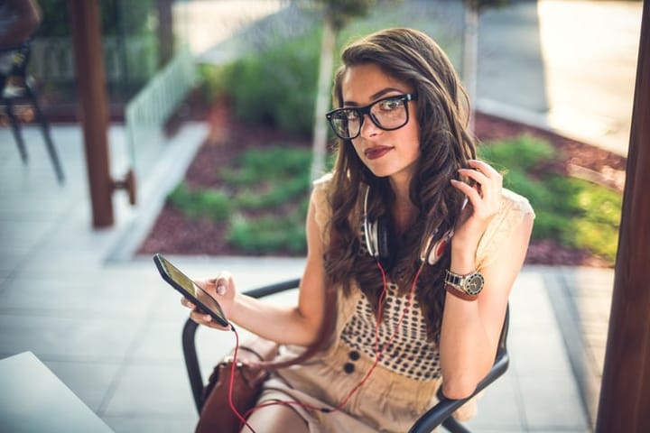 Elegant woman texting in restaurant,glasses and headphones