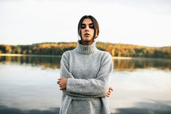 serious woman with arms crossed by water