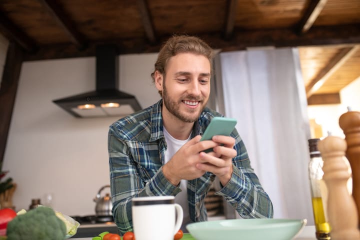 man smiling texting coffee shop