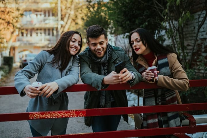 three people looking at a smartphone