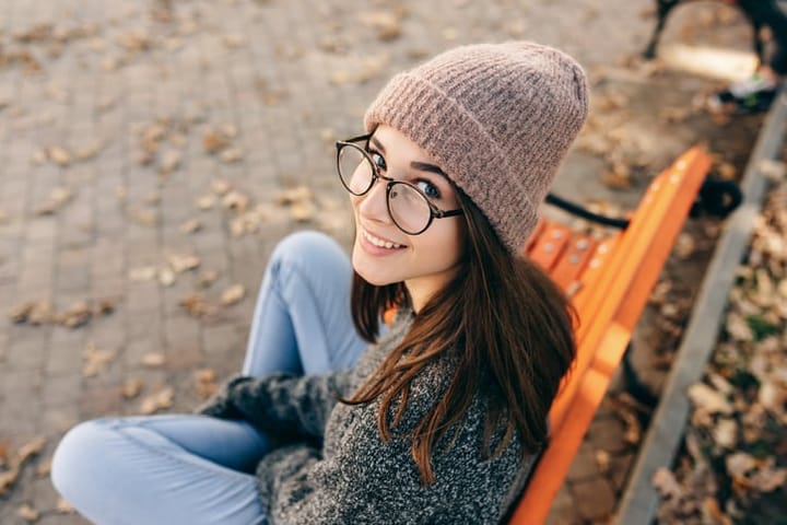 woman with glasses and beanie hat smiling