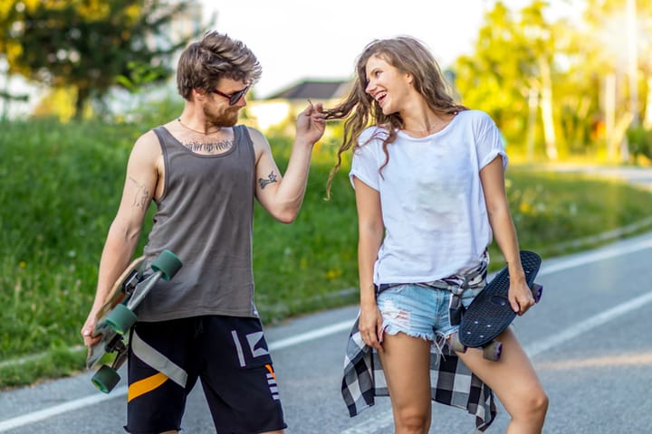 couple flirting outside with skateboards