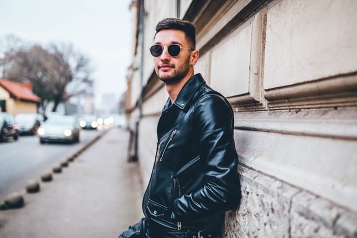 man in leather jacket and sunglasses standing casual