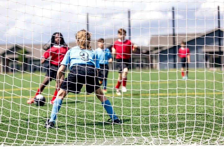 A mixed gender soccer team makes a goal attempt.