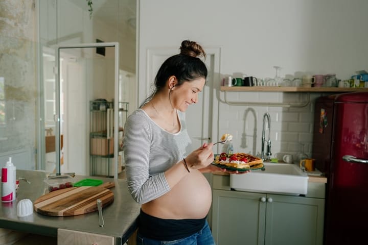 pregnant woman eating in kitchen
