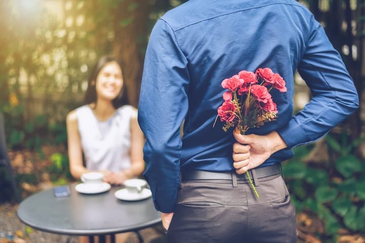 man surprising woman with flowers