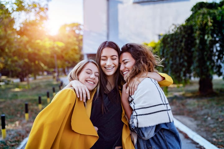 three female friends hugging outside
