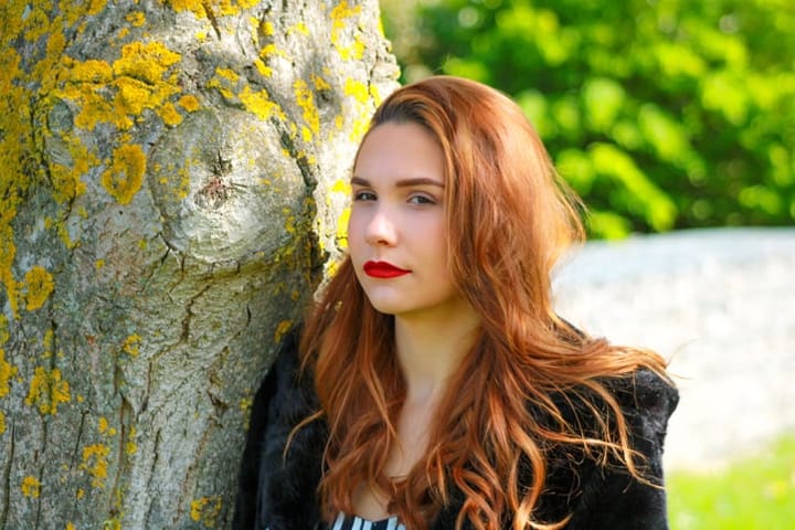 ginger haired woman beside a tree